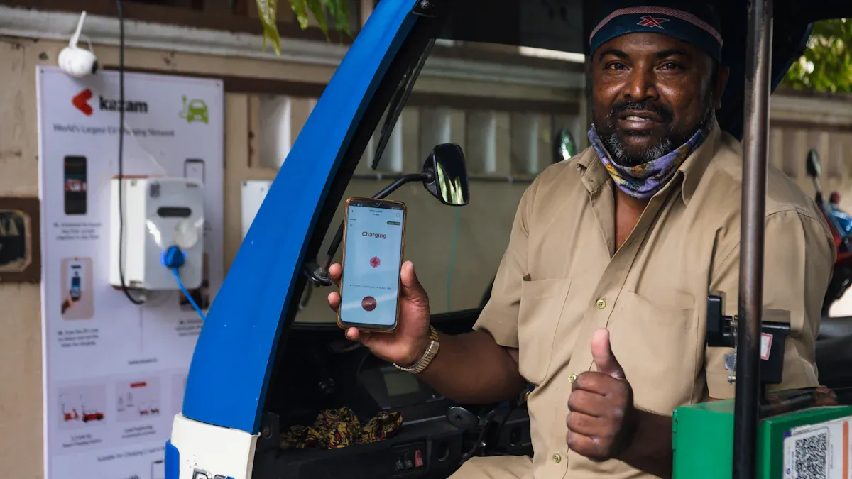 Un hombre sentado en un coche sostiene un smartphone en el que aparece la palabra "Cargando" en una mano y hace un gesto de pulgar hacia arriba a la cámara con la otra mano. 